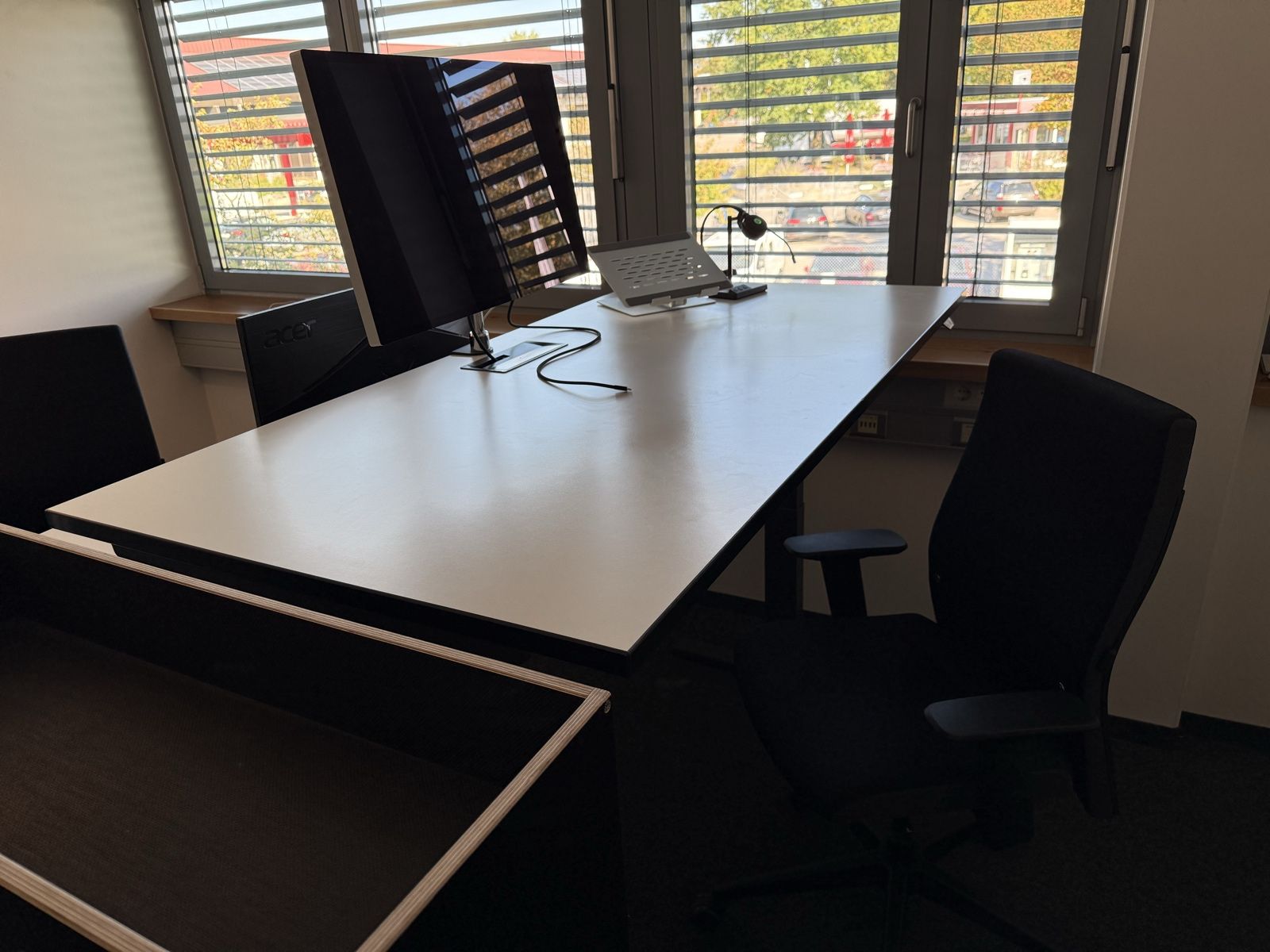 Höhenverstellbarer Schreibtisch mit ergonomischem Bürostuhl am Fenster